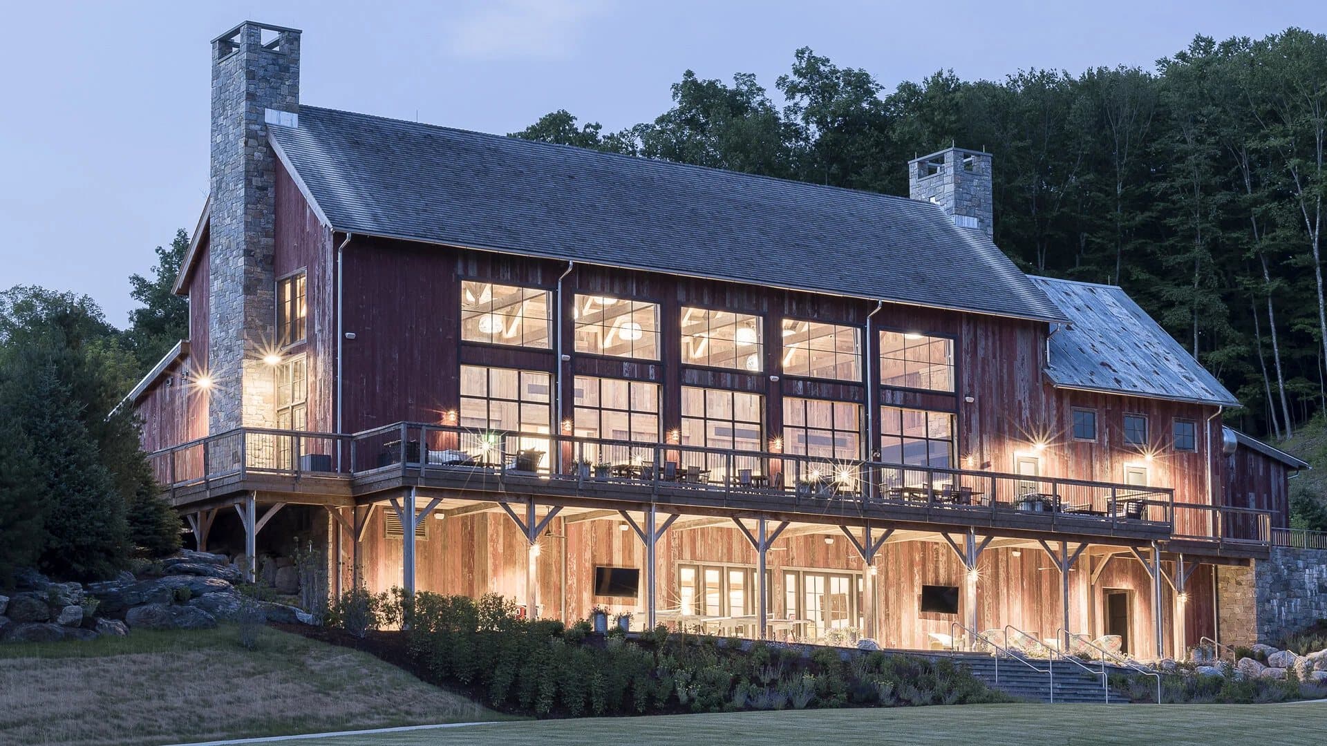 Reclaimed-wood barn estate at dusk with warmly lit windows